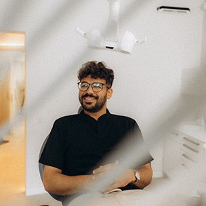 Patient with black glasses smiling in treatment chair
