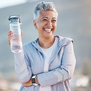 Woman smiling with water bottle on hike outside