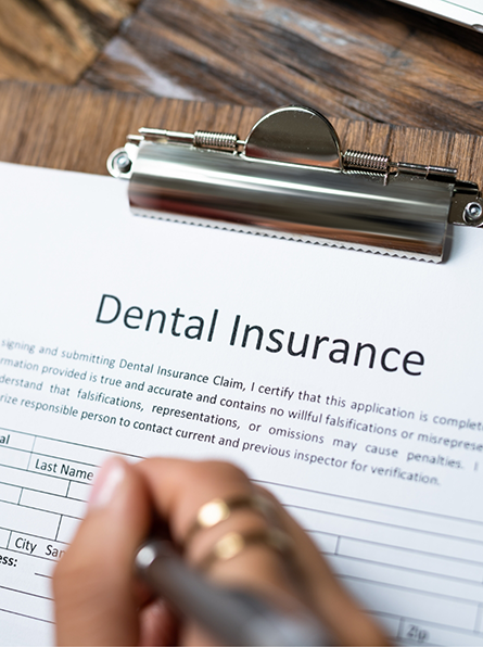 Filling out dental insurance form on clipboard
