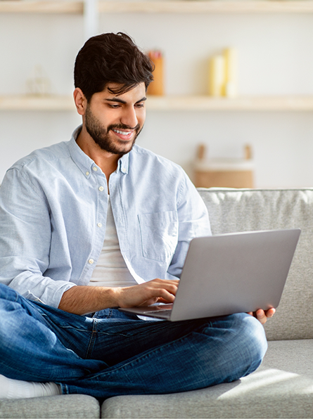 Man sitting on couch typing on laptop