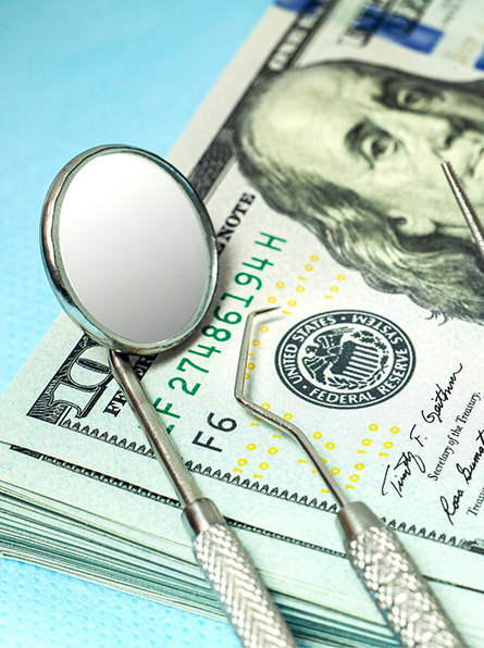 Dental instruments lying on top of hundred dollar bills