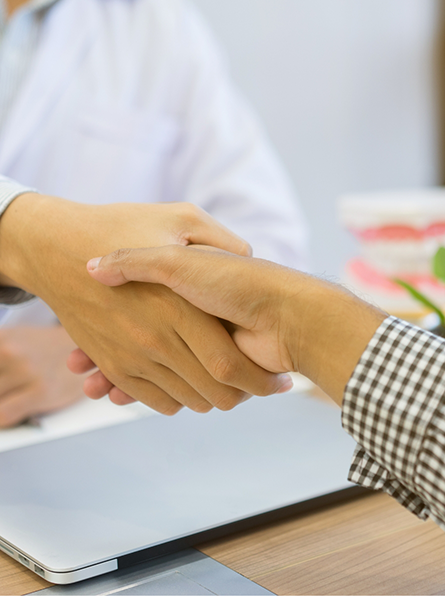 Shaking hands over desk with laptop