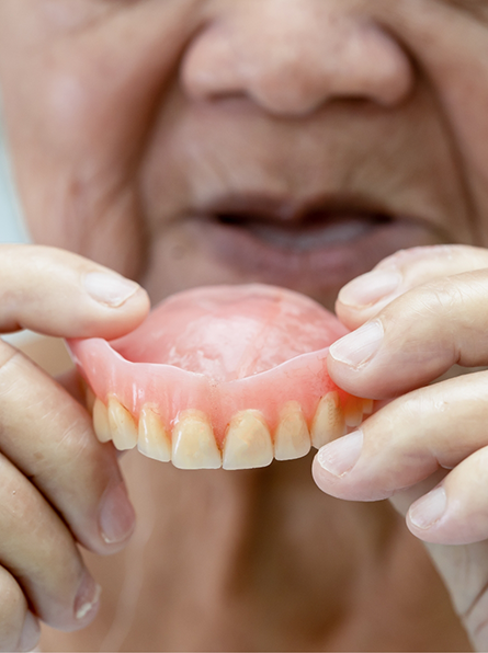 Senior holding full dentures